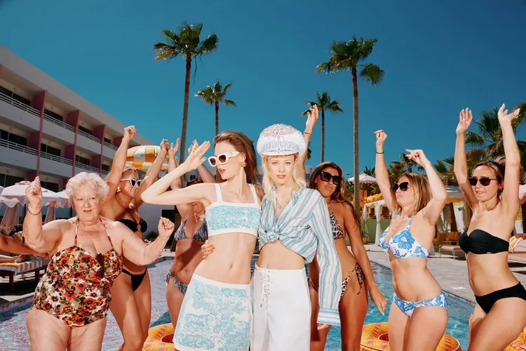 Grupo de gente con looks setenteros junto a la piscina